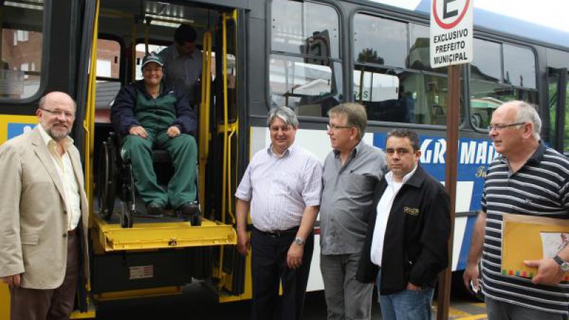 Autoridades em frente ao ônibus adaptado e um cadeirante no elevador lateral do mesmo. Foto: Ricardo Bertolucci Reginato