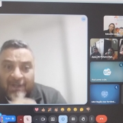 Foto- tela do computador, nela em çrimeiro palno e em uma janela maior o presidente da faders realiza sua fala, ao lado direito várias outras telas ( quadros) com as fotos dos demais participantes da reunião on line. Fim da descrição 